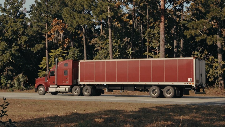 Red sleeper truck on I-16 through rural Georgia pine forest, representing the broader Georgia trucker dating community